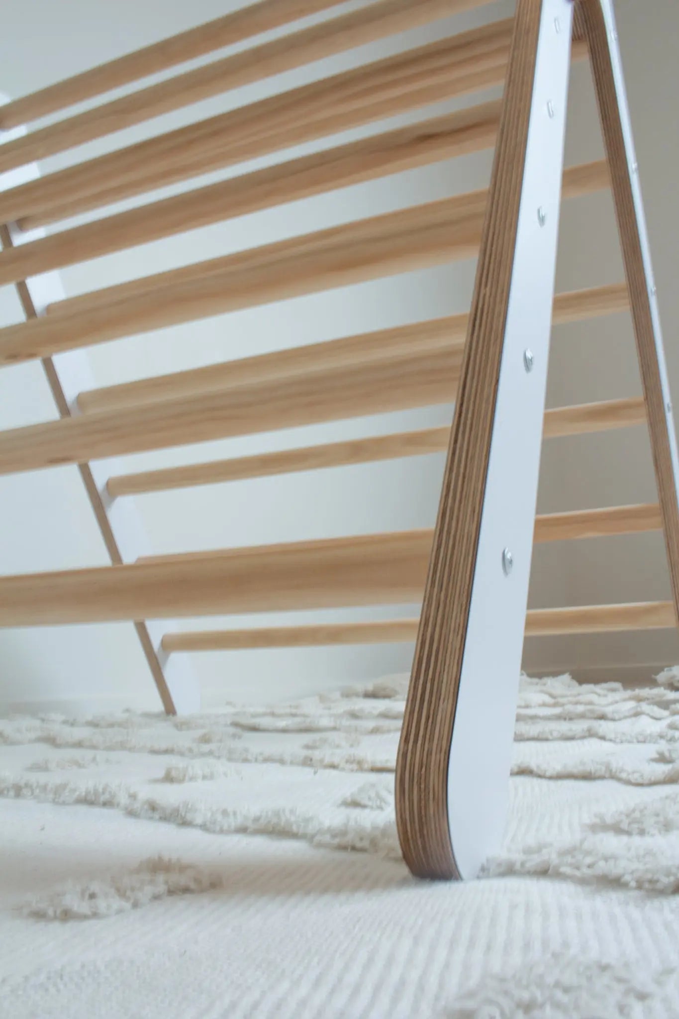 a close up image featuring the leg and rungs of a white climbing triangle