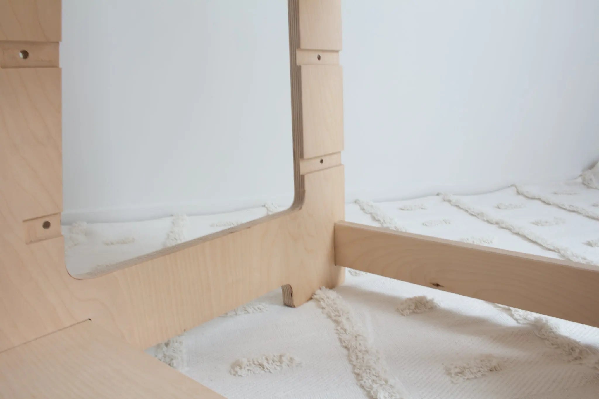 A close up image showing the base of a natural wooden learning tower. The image shows the high quality of the wood and two different adjustable positions.