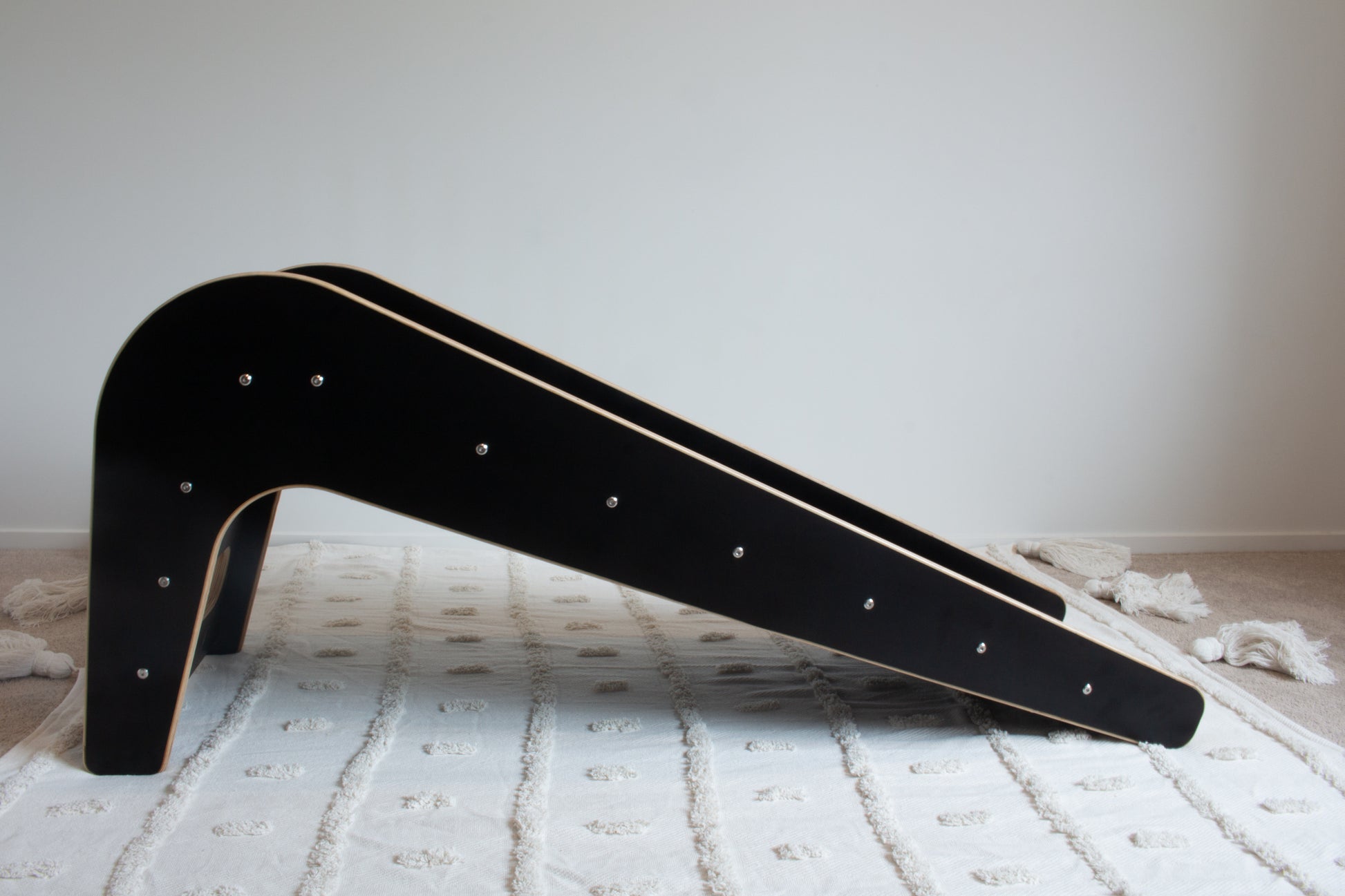 A side on view of the black wooden slide with its screws