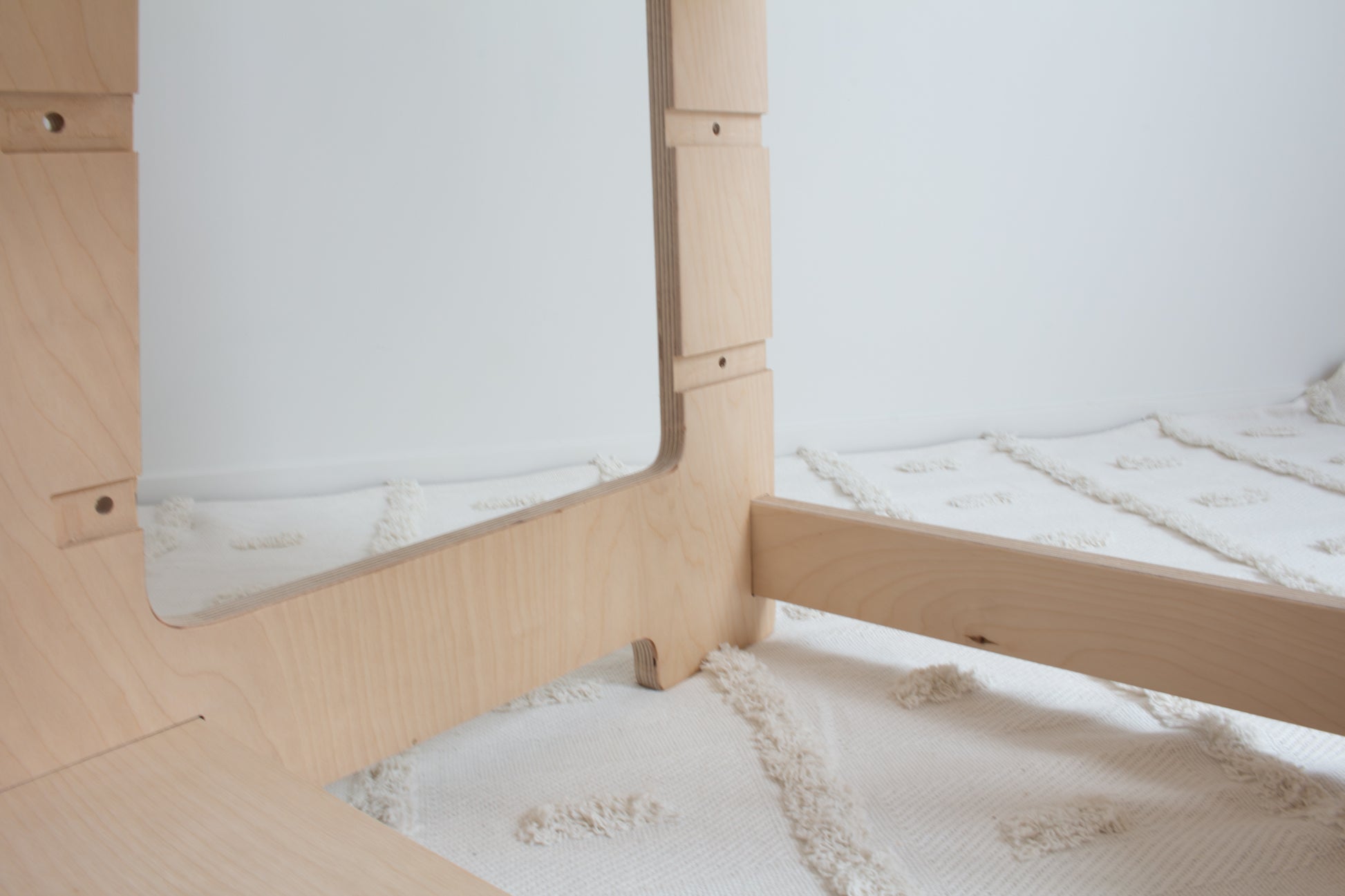 A close up image showing the base of a natural wooden learning tower. The image shows the high quality of the wood and two different adjustable positions. 